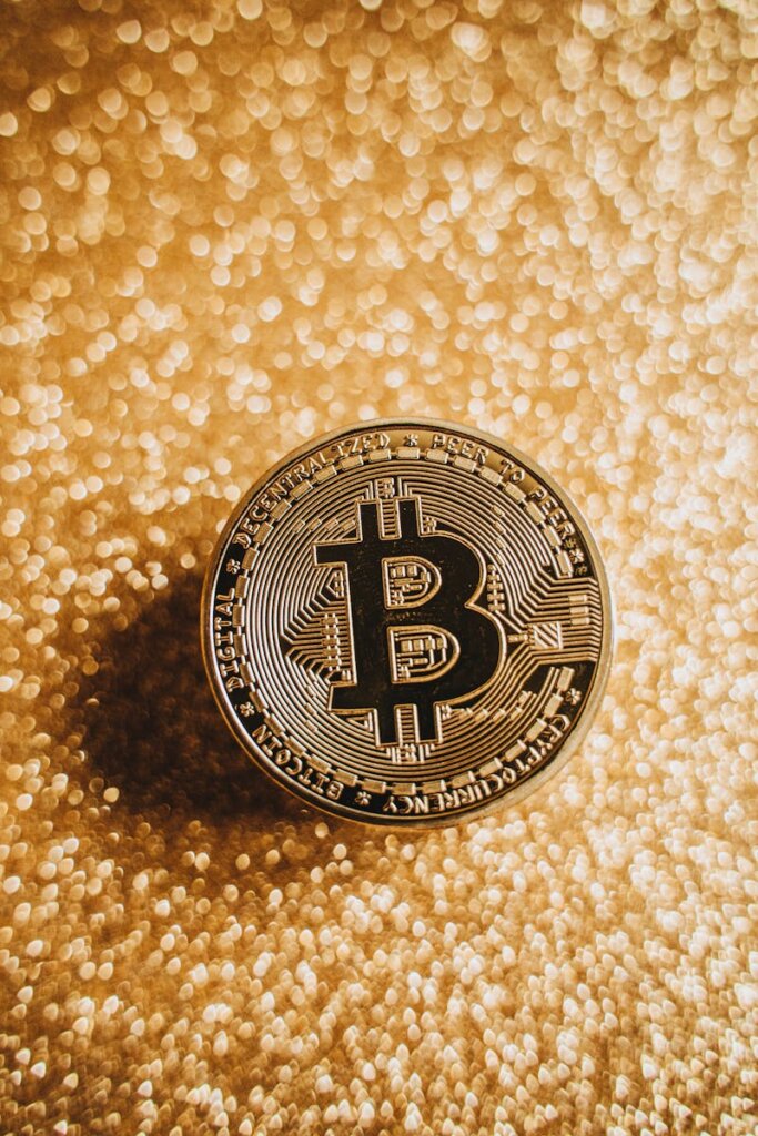 A close-up of a Bitcoin coin against a shimmering gold background, symbolizing digital currency and finance.